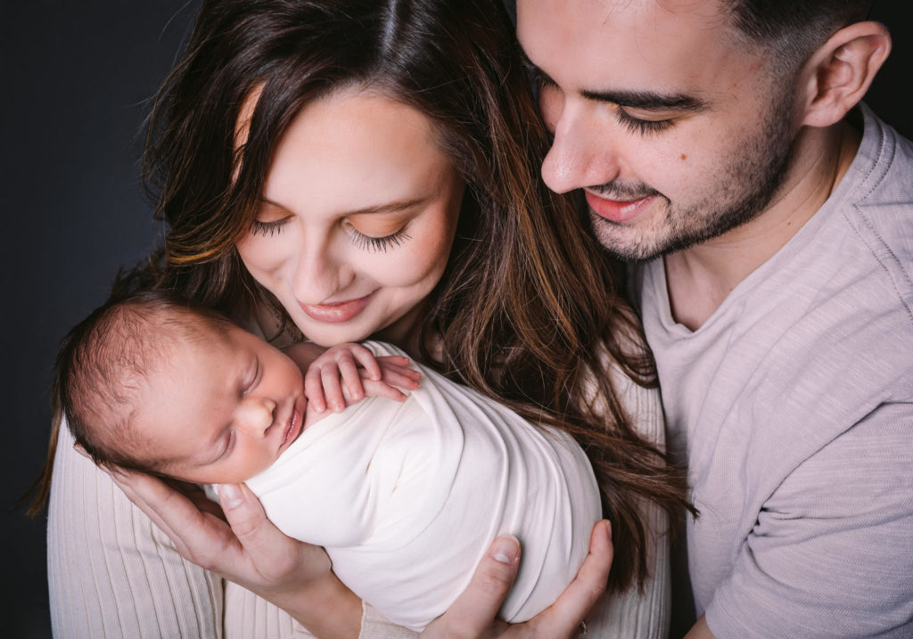 new parents smiling at their newborn at Manchester studio